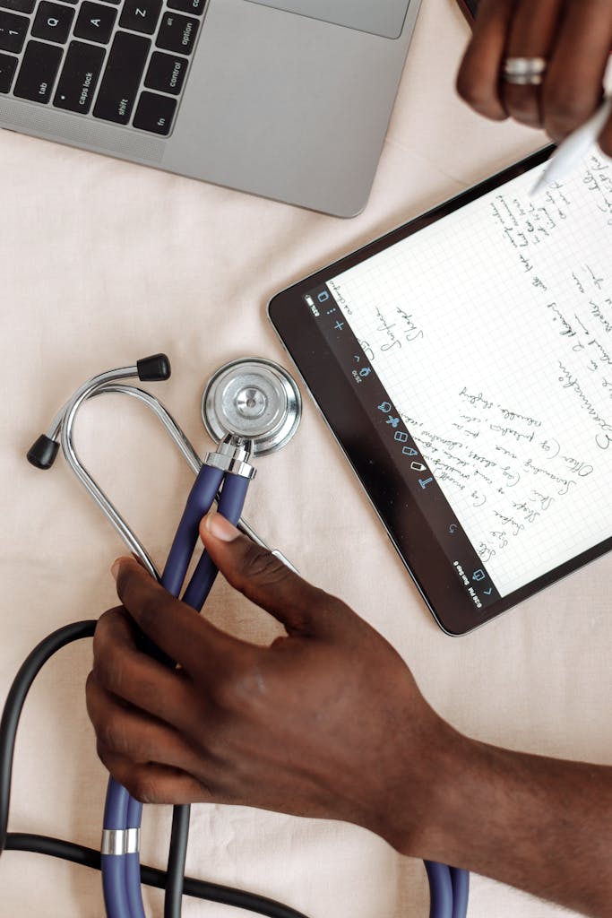 Life Sciences and Healthcare 14 A close look at hands holding a stethoscope next to a tablet showing medical notes.