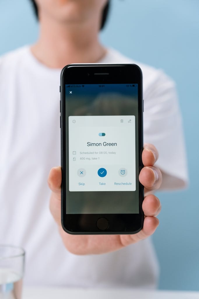 Pharma 14 Close-up of a smartphone displaying a medication reminder app held by a faceless person.