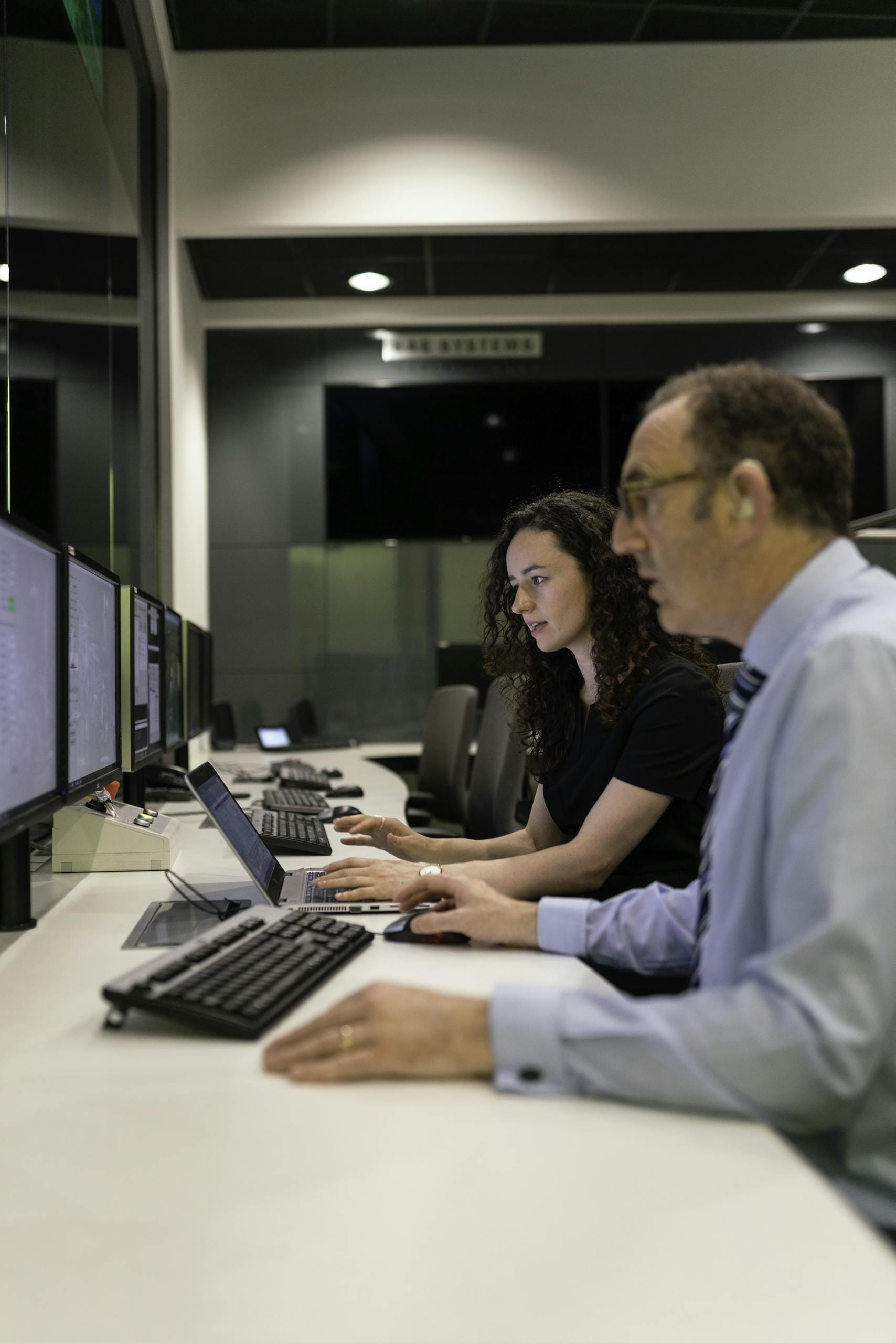 Government & Public Services 14 Engineers working together in a modern control room focused on simulation and testing.