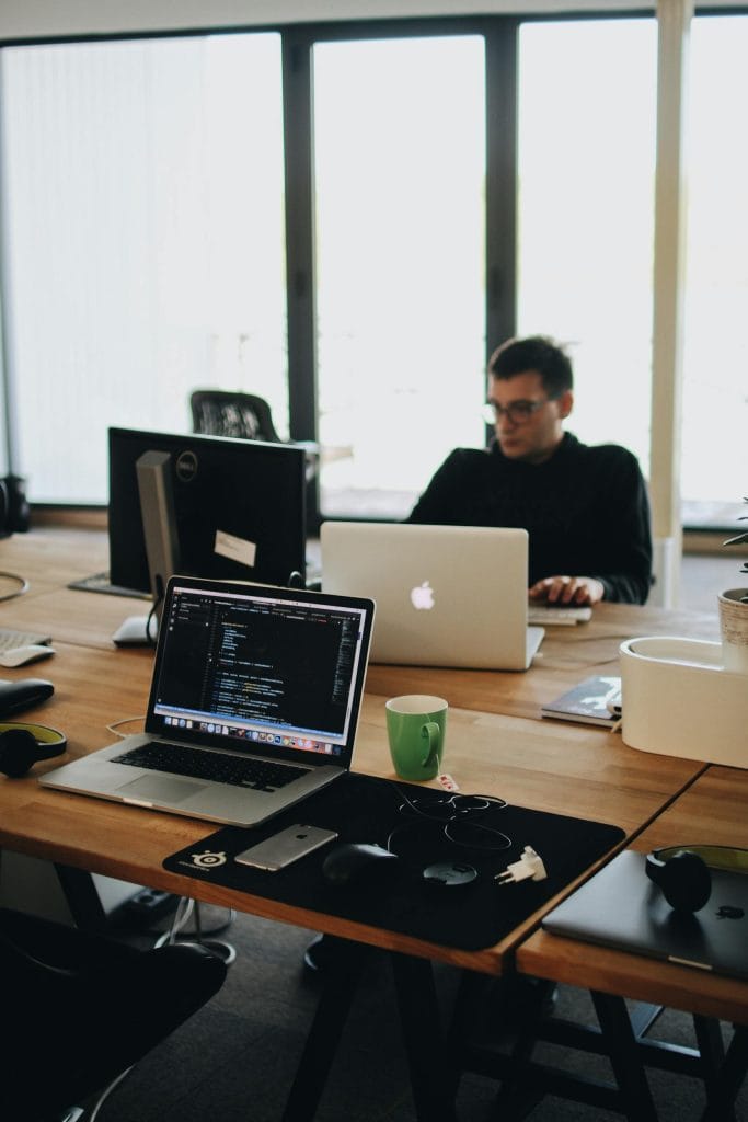 Telecommunication 14 A web developer working on code in a modern office setting with multiple devices.
