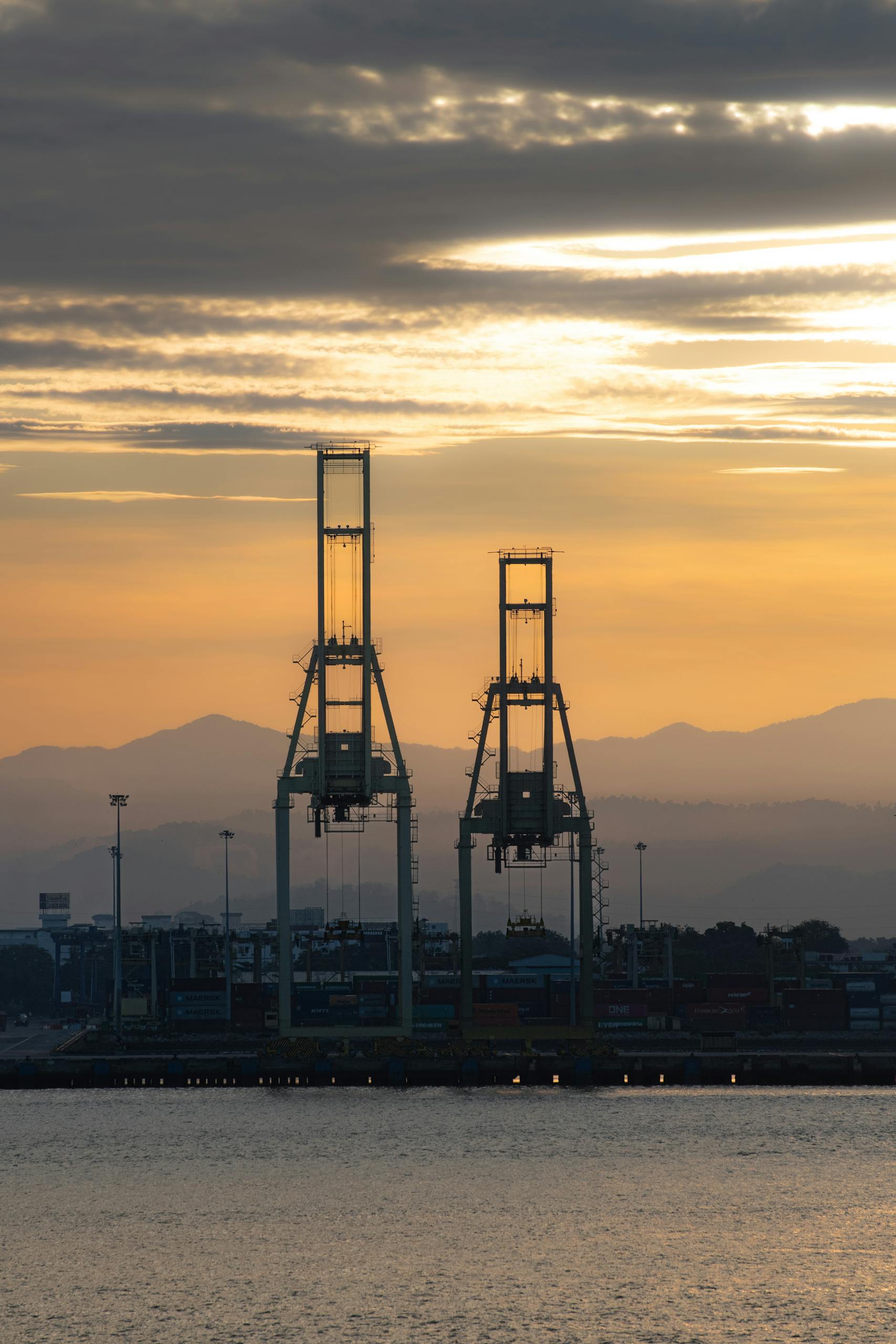 Serene sunset view of cargo cranes at Penang Port, Malaysia highlighting industrial beauty against nature.